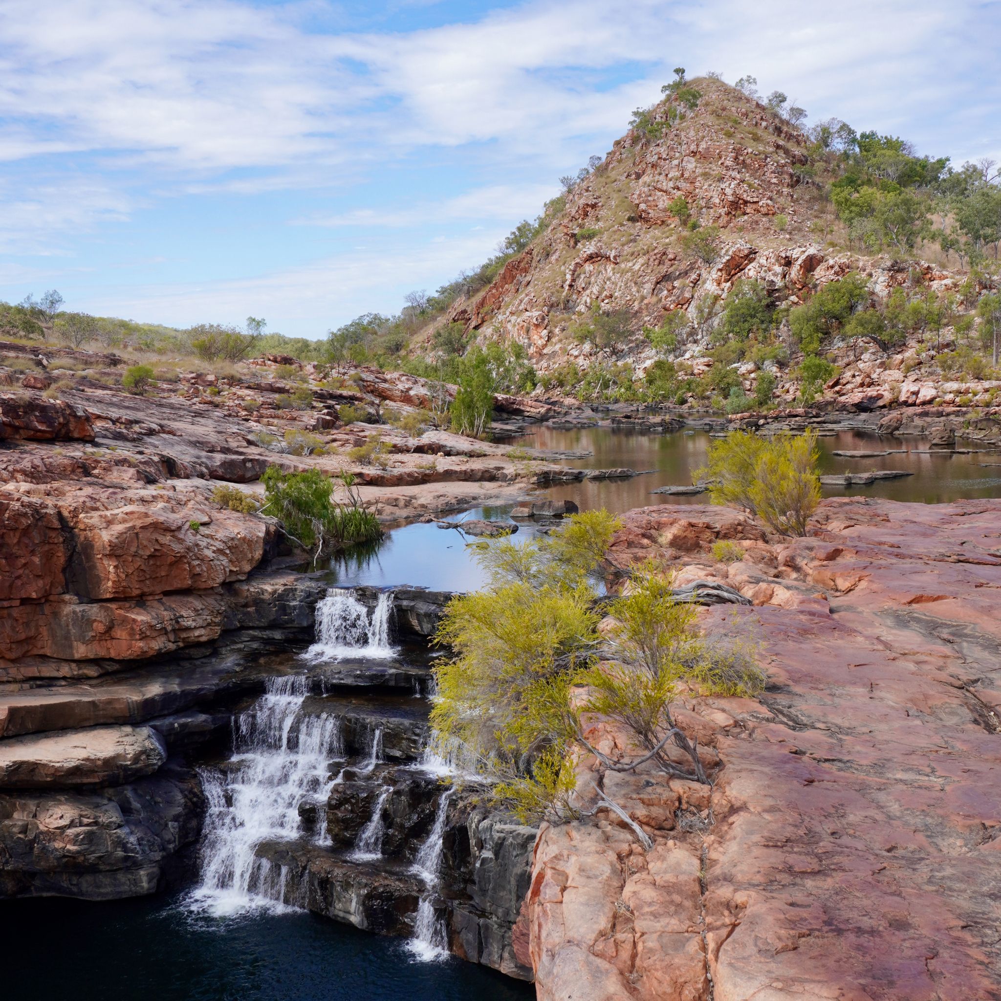 A river at Bell Creek cascading down into a large pool with a mountain in the background.