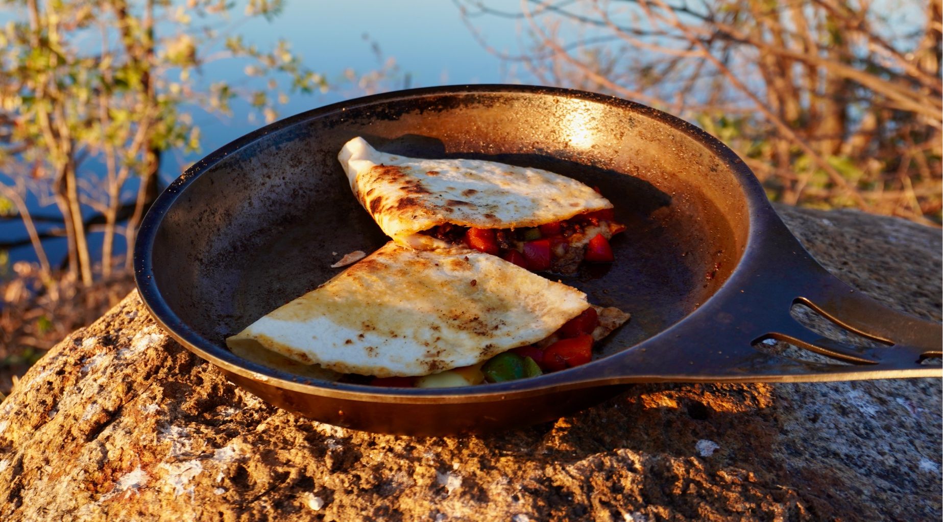 A picture of a quesadilla cut in half with minced beef and capsicums in a cast-iron pan.