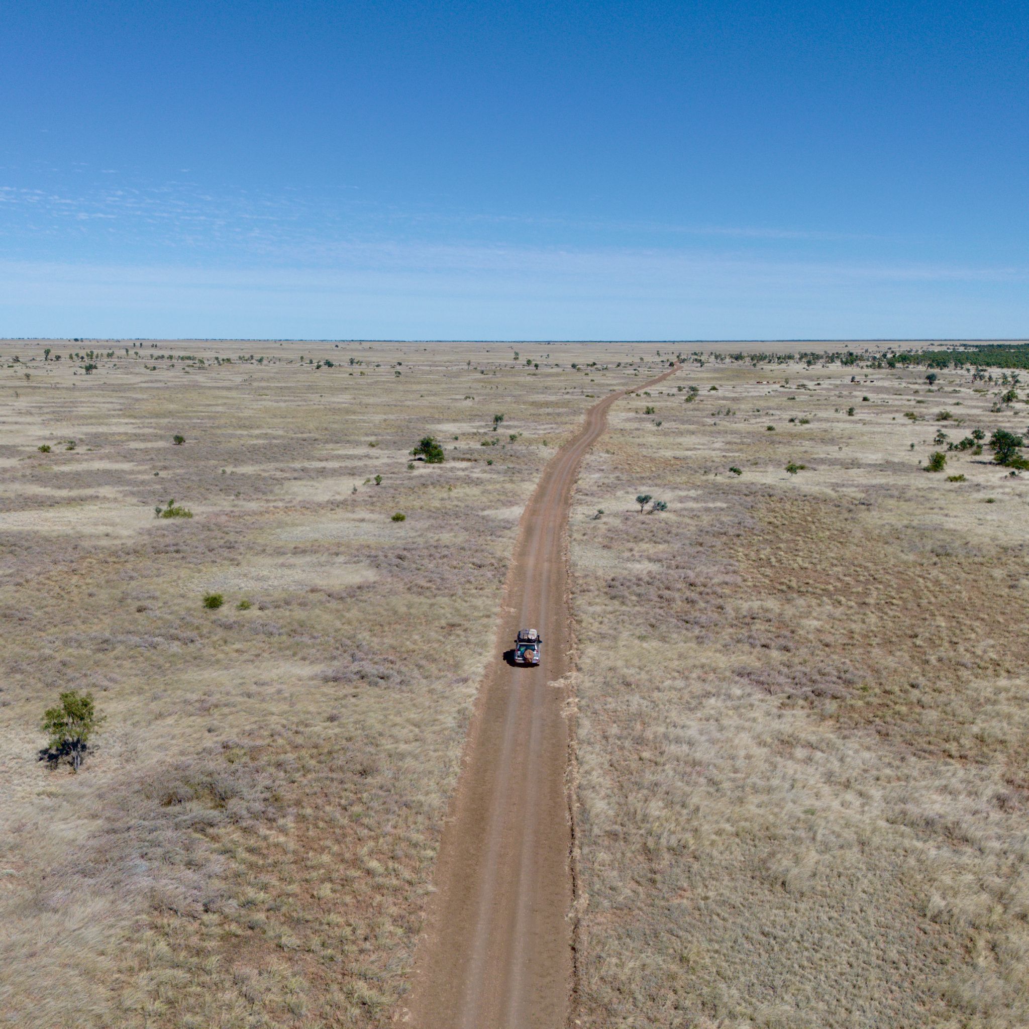 A single car on a dirt road photographed by a drone.