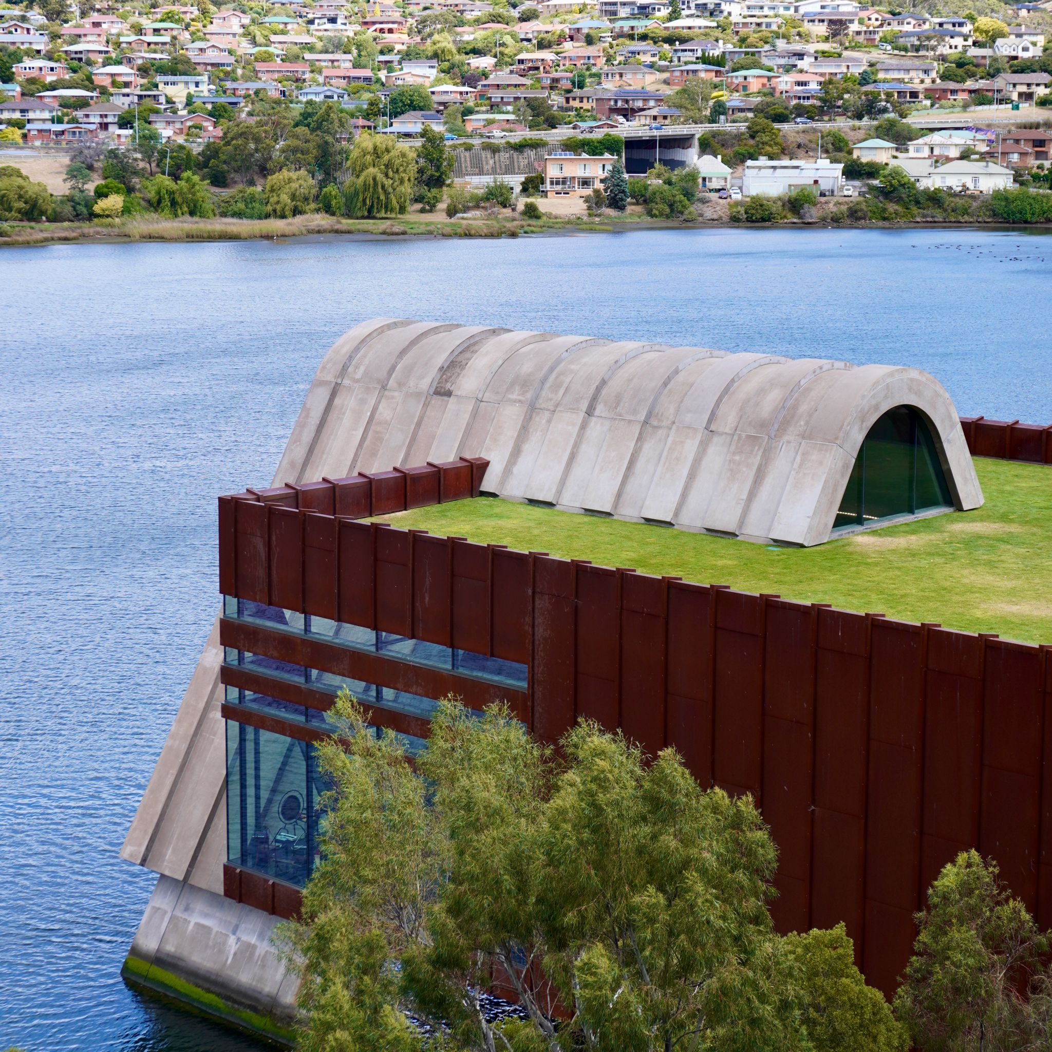 A building of the MONA, the Museum of Old and New Art in Tasmania, with the city in the background.