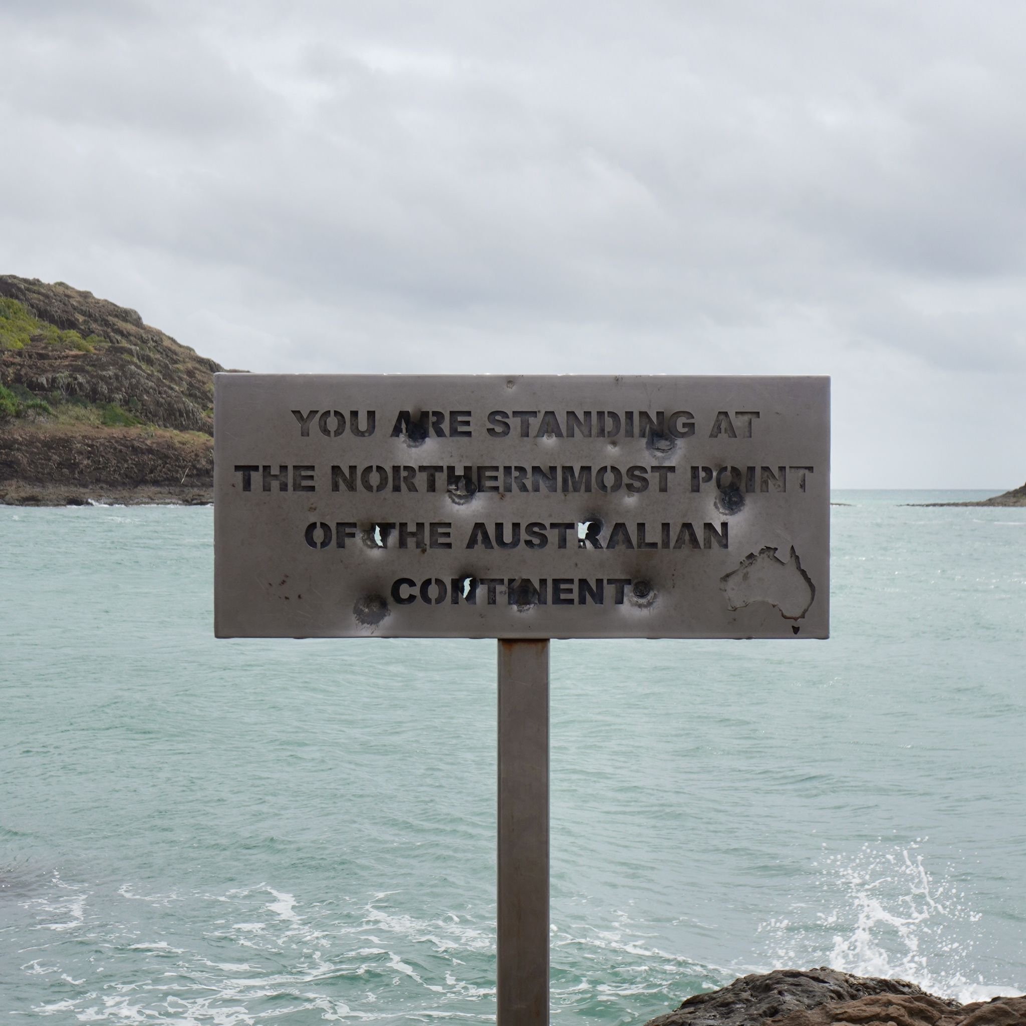 A metallic sign reading 'You are standing at the northernmost point of the Australian Continent'.